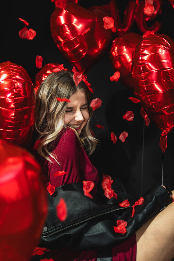 Portret Studio Walentynki Portret kobiety wśród czerwonych balonów i płatków róż podczas walentynkowej sesji.